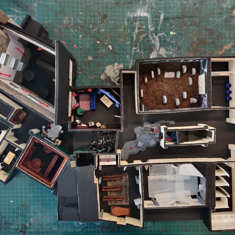 Photograph of the full set design taken from above- the set model includes a church, graveyard and pub. Created from various materials, including cardboard. 