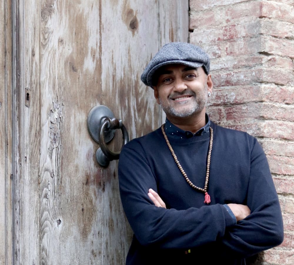man wearing har standing against a brick wall
