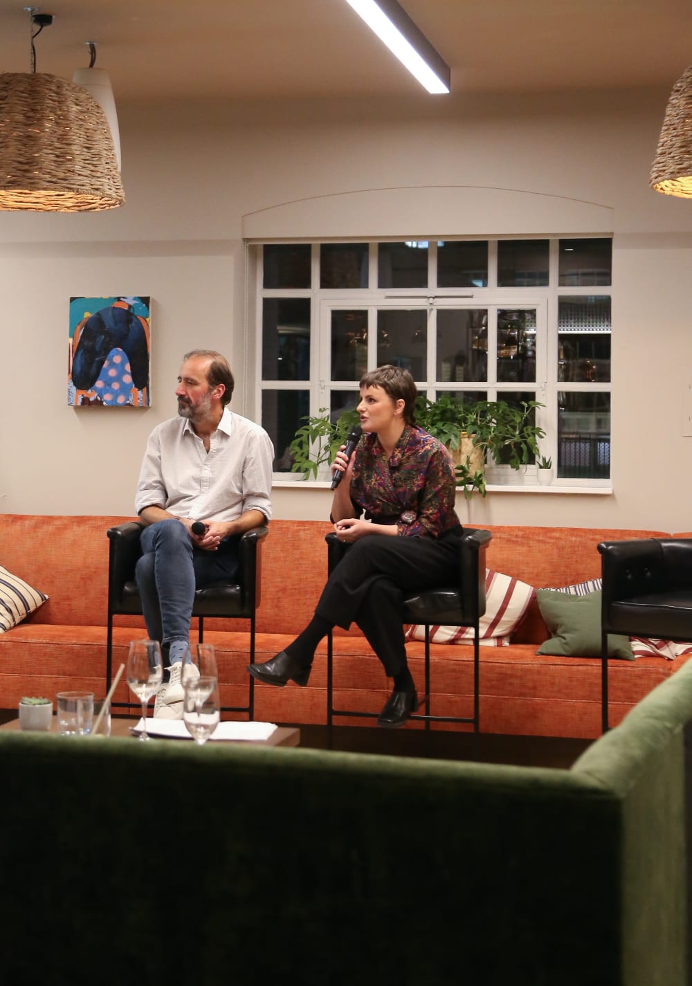 A shot of a man and woman on guest speaker chairs, answering questions on a microphone