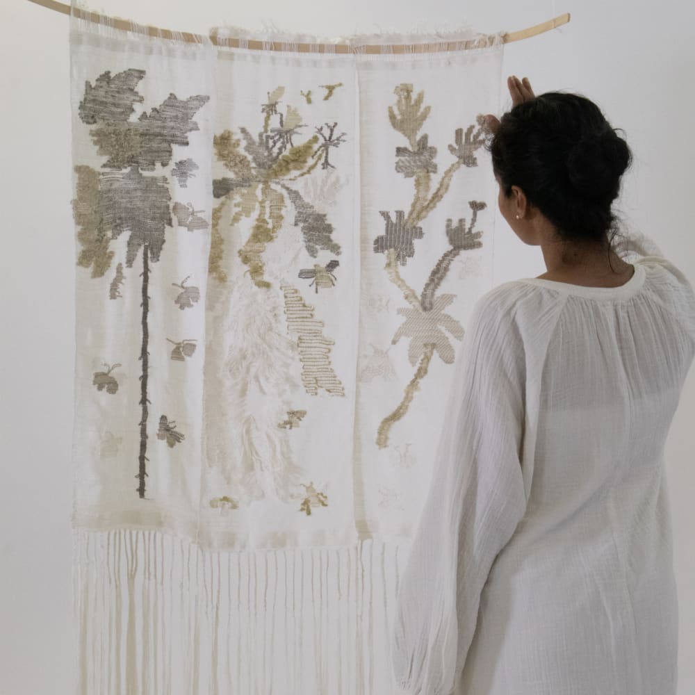 A bright shot of a woman looking at a flowery tapestry on the wall