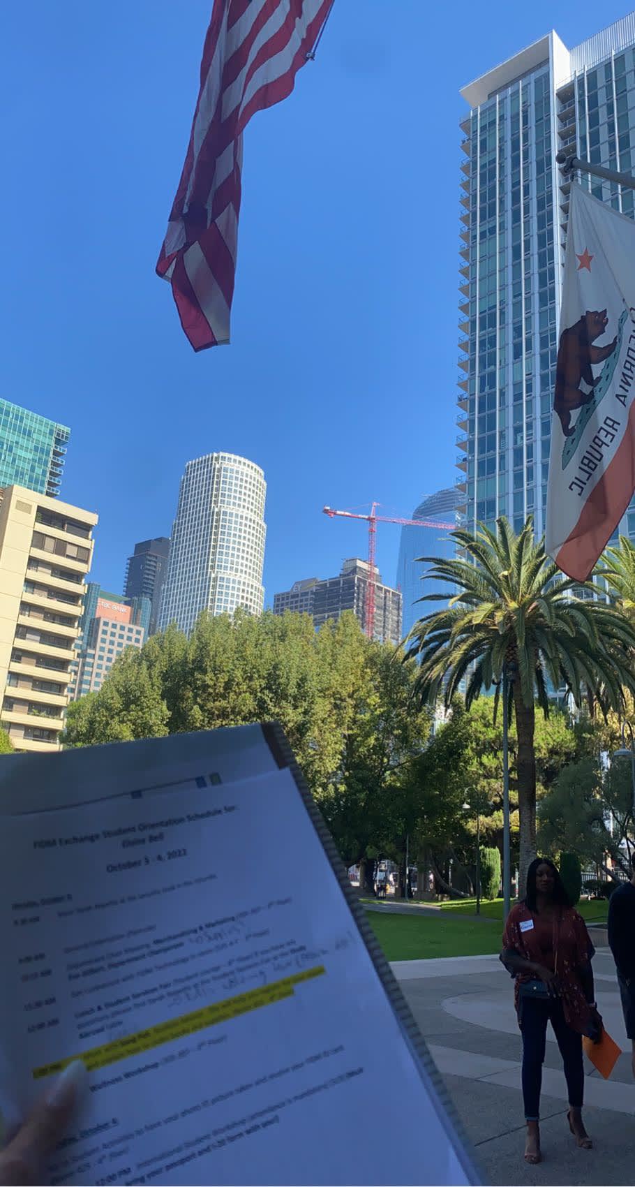 Eloise holding her project up, with blue skies and the campus in the background