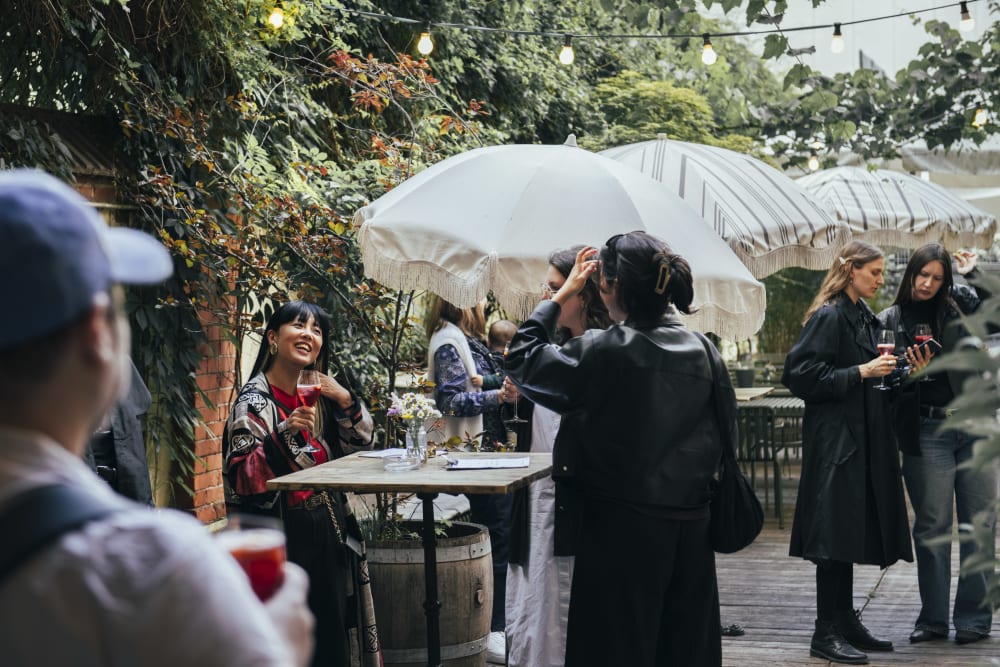 Guests in the garden with fairy lights, lots of plants and umbrellas