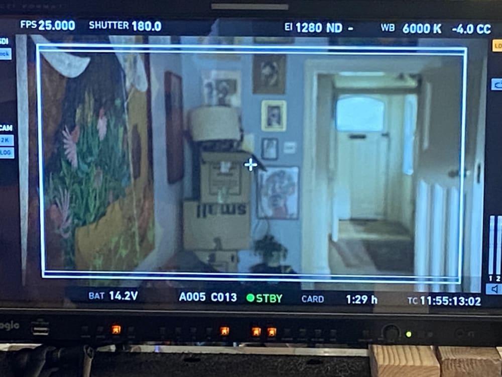Looking through a camera monitor at a film set of a house with paintings visible