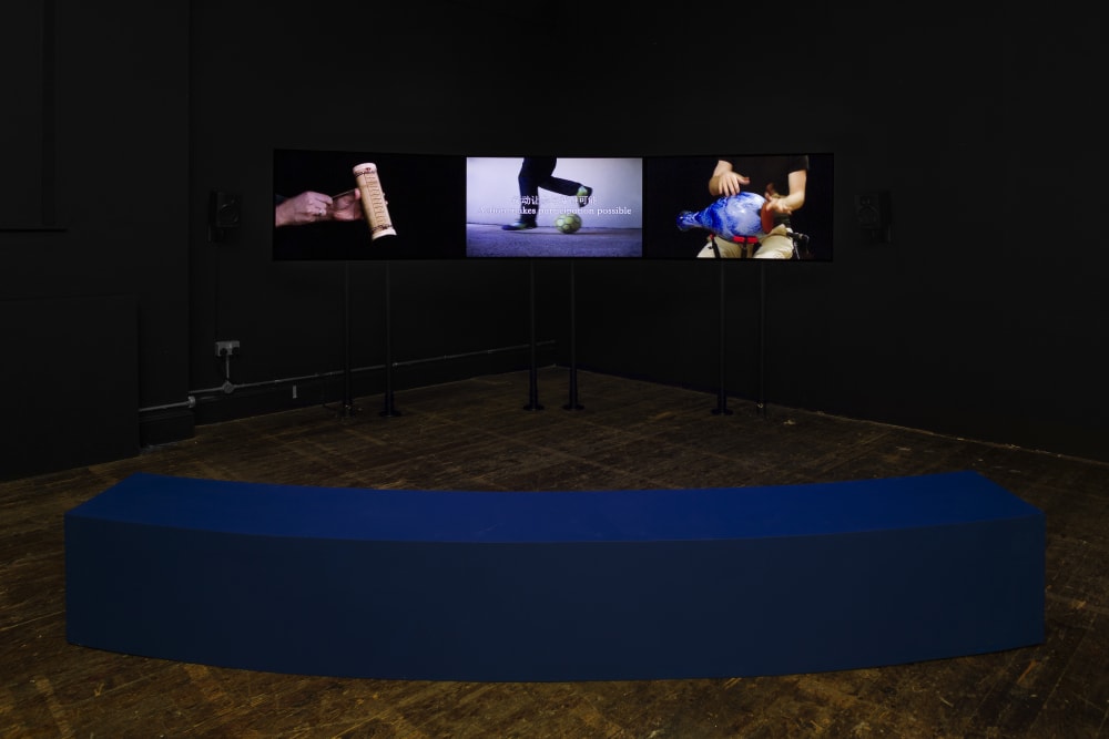 Three video screens in a dark room