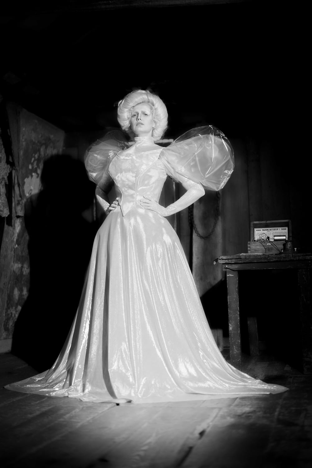 A woman stands in a white Victorian-style dress.