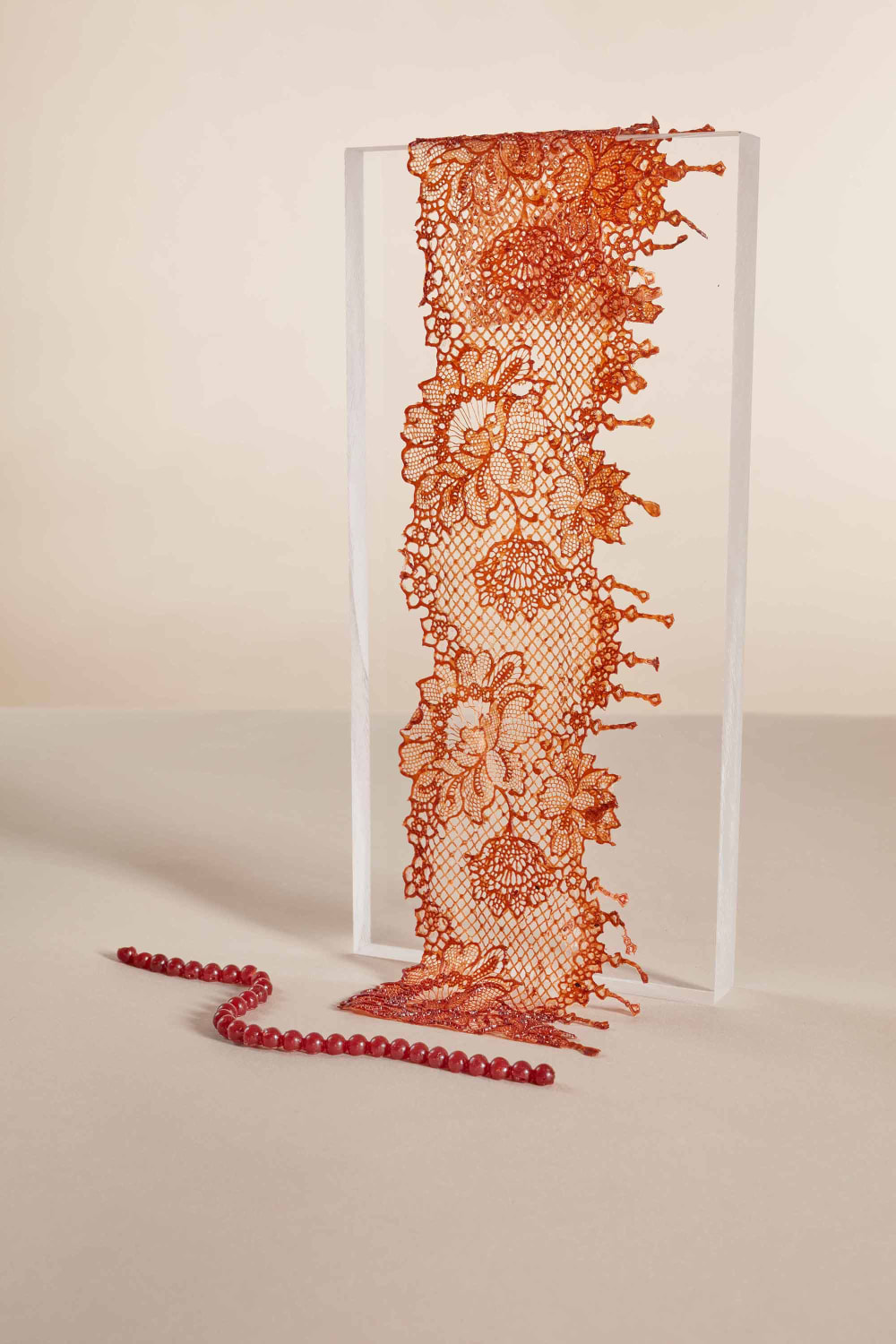 An intricate lace-like pattern sample is displayed over a transparent plinth.   