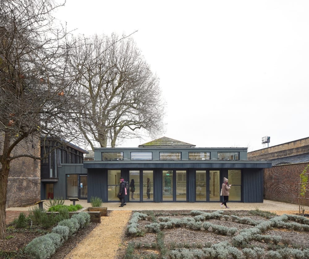 a single story glass building behind a herb garden