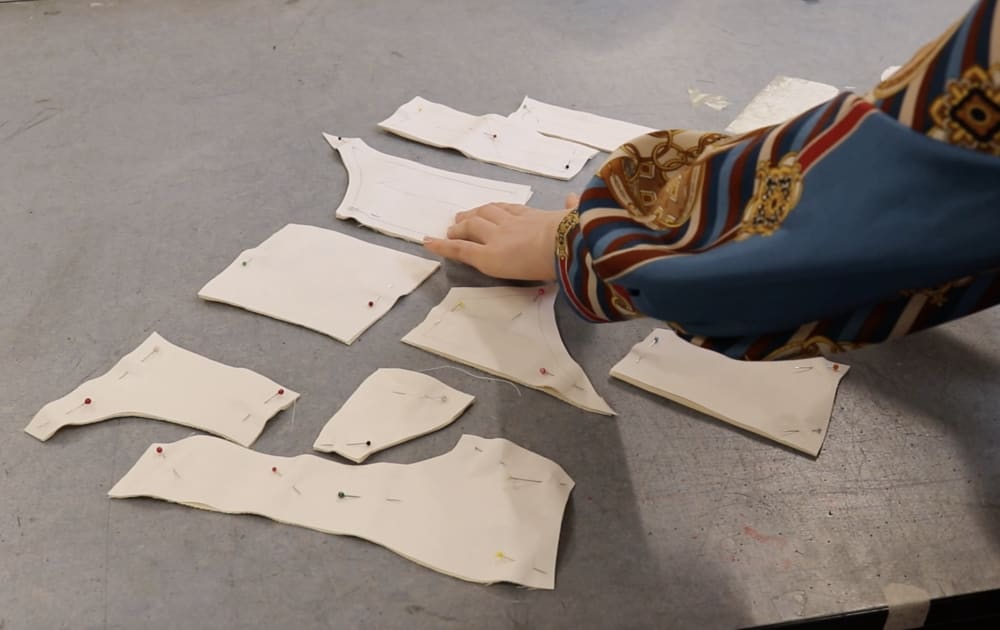 A pair of hands sorting out pattern pieces for a garment.