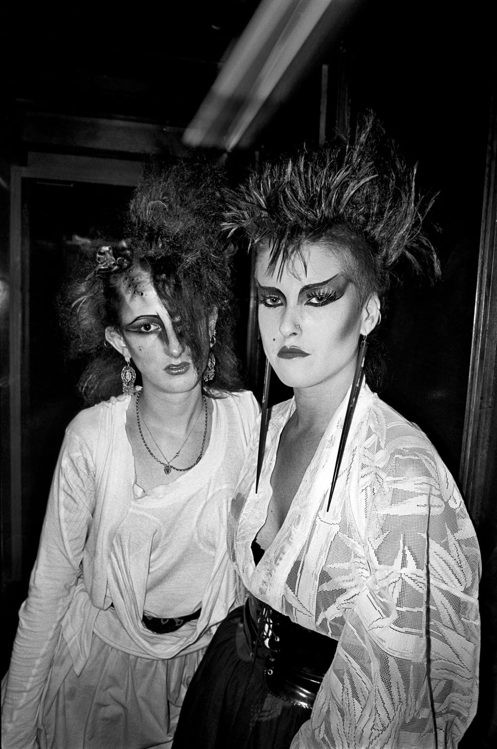a black and white photograph of two goths