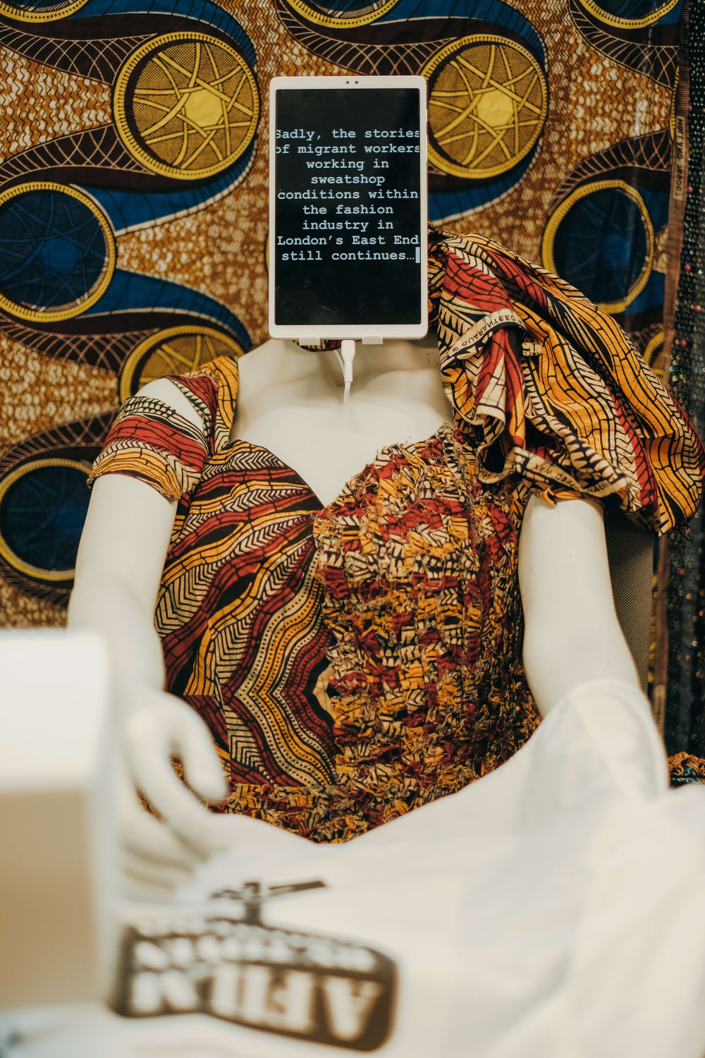 dress on a mannequin with fabric background and a sign