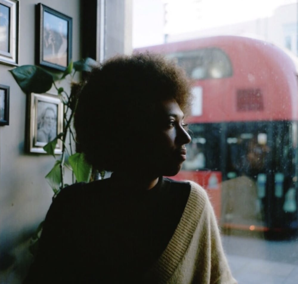 Photograph of Ada Cotton sitting by a window with plants behind them
