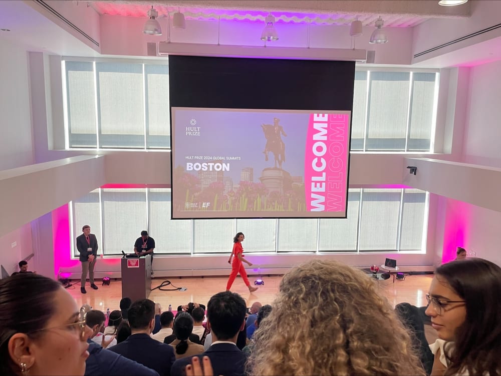 Auditorium with projector, stand and microphone, and crowd of people.