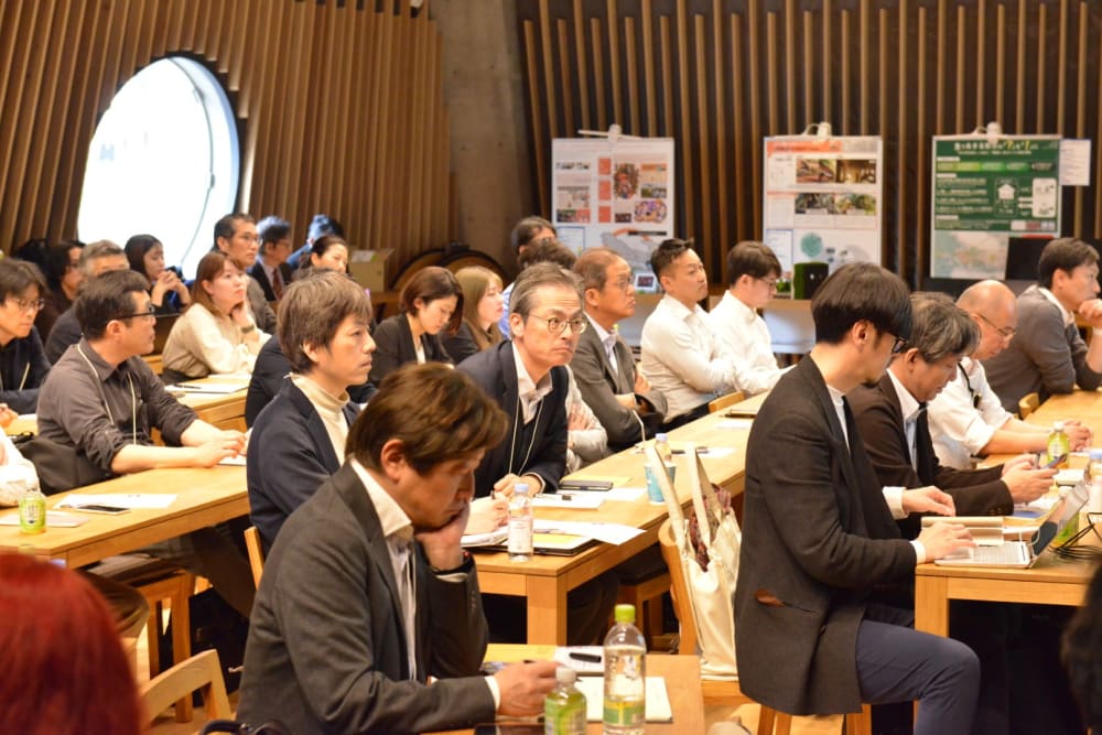 People wearing suits sat behind desks in an auditorium.