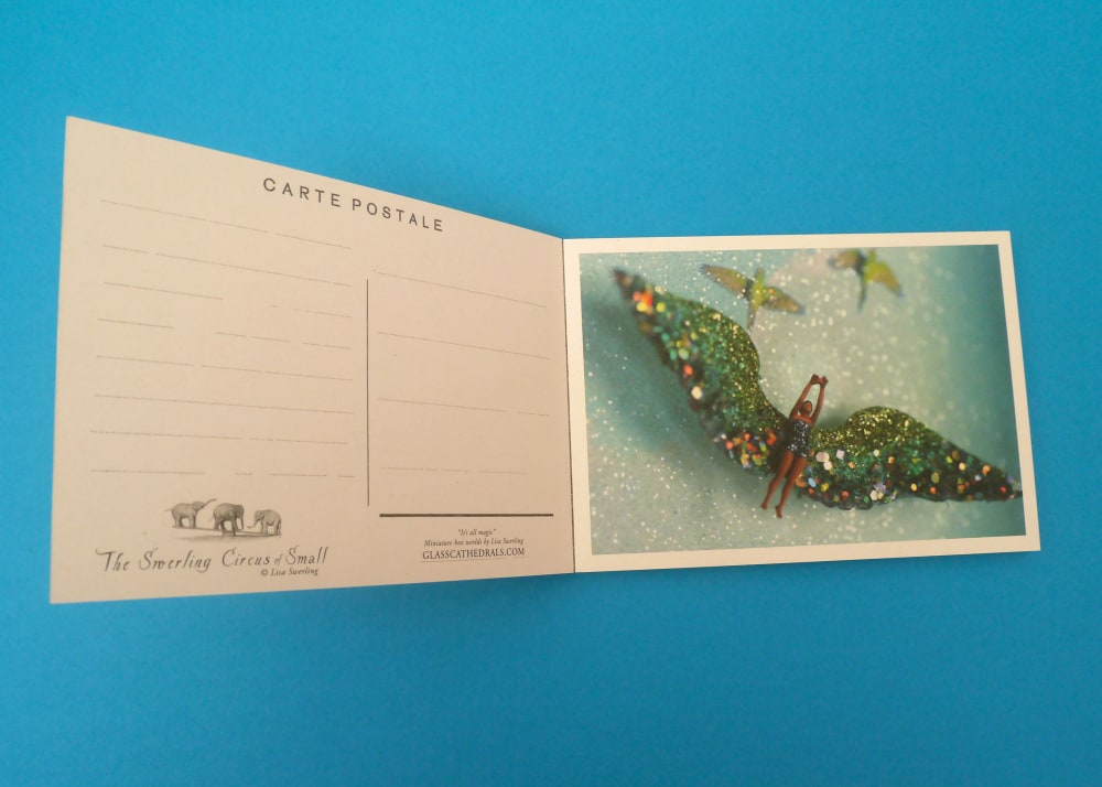 A postcard with a plastic figure with wings on the front