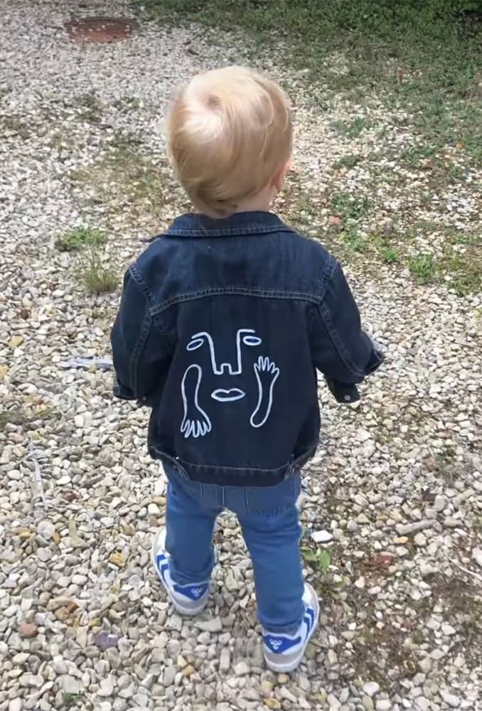 a little boy wearing a denim jacket