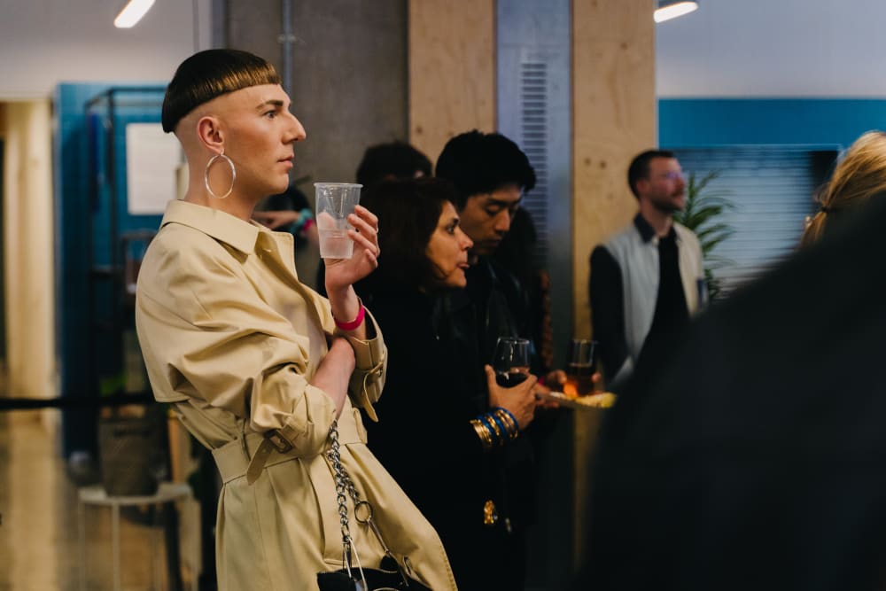 Guest standing in profile to the camera. They're holding a plastic cup and looking straight ahead. 