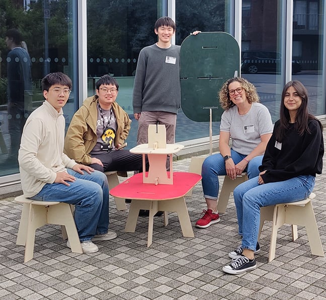 Five students posing with a set of modular furniture outdoors.