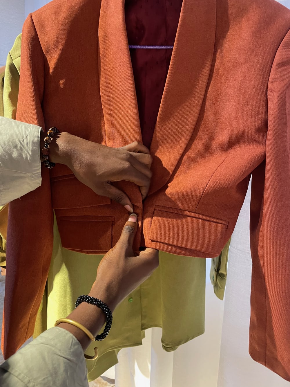 An orange and yellow blazer being touched by a person's hand.