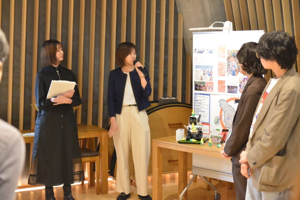 Four people presenting a poster in an auditorium.