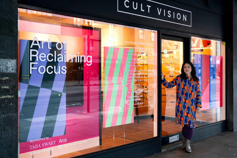 picture of June Mineyama-Smithson smiling and standing in front of Cult Vision’s window