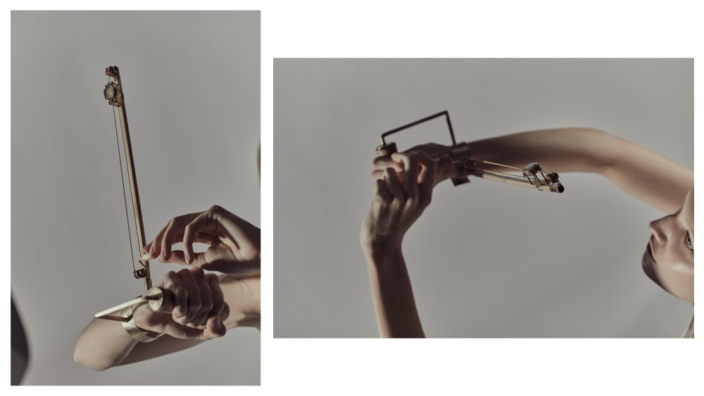 Abstract composition featuring hands interacting with a mechanical device, set against a neutral gray background. The tone is artistic and contemplative.