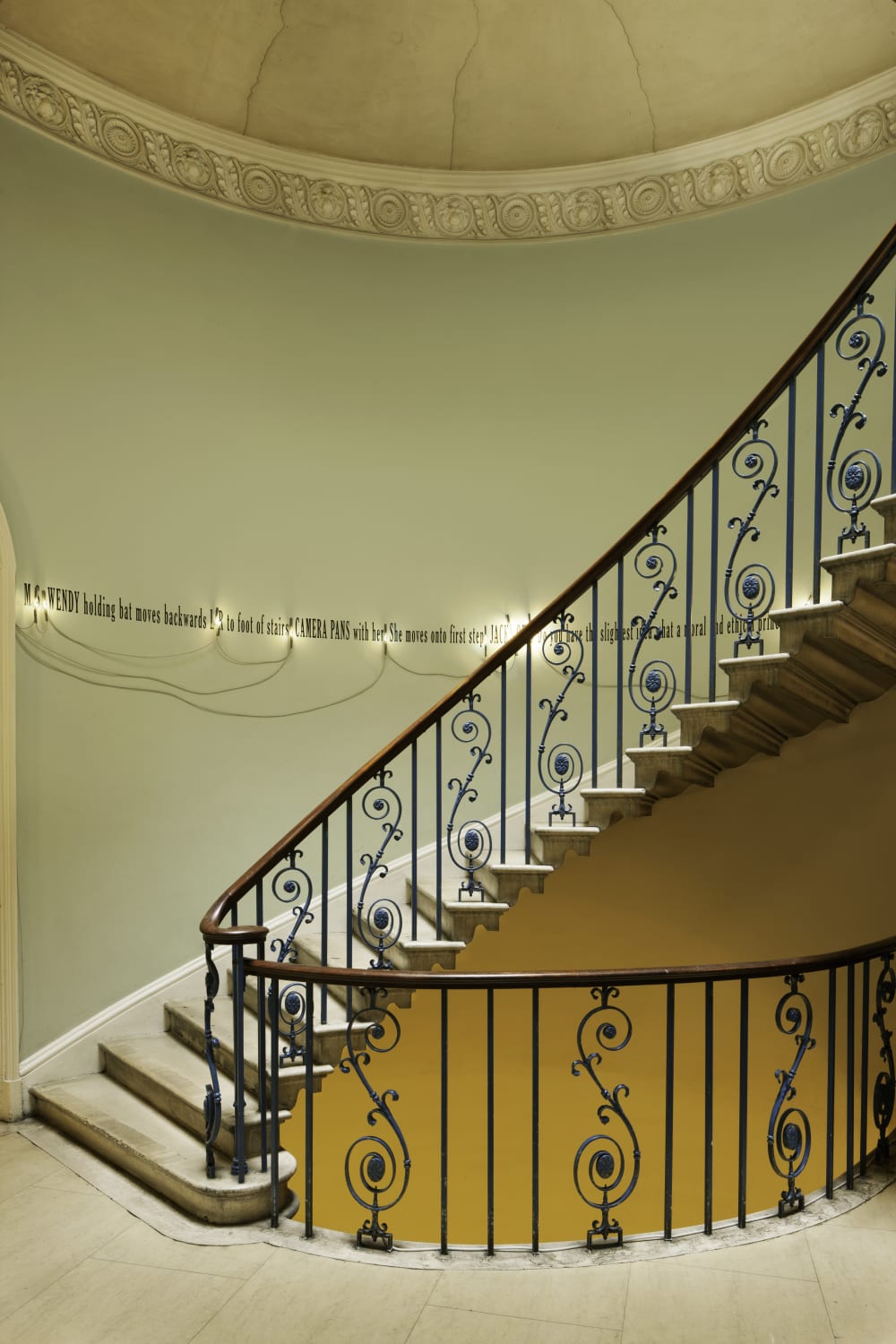 Black writing illuminated with lights going up a staircase