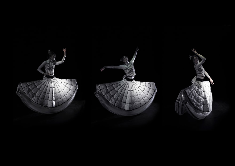 three images of model dancing against a black background, in wearable piece created as an alternative individual mobile living space, shaped as a two piece top and crinoline inspired dancer's skirt