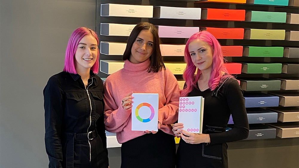 Images shows the 3 female winners standing next to each other holding a finished copy of the Munken Agenda