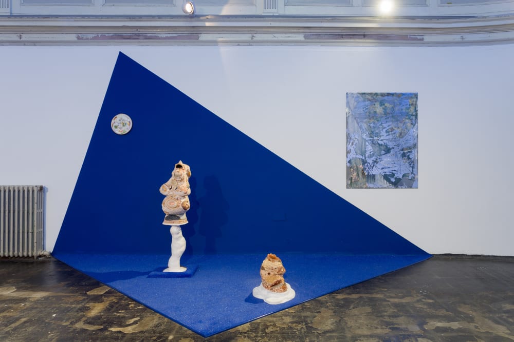 two sculptures on an asymmetrical blue cloth in a gallery