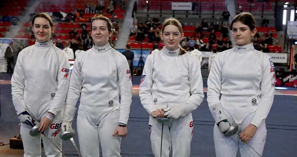 4 people posing for a picture in their fencing attire.