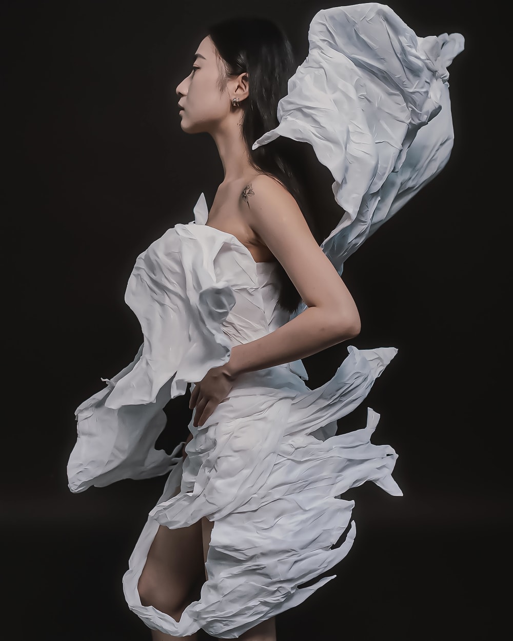 model in white garment against black background