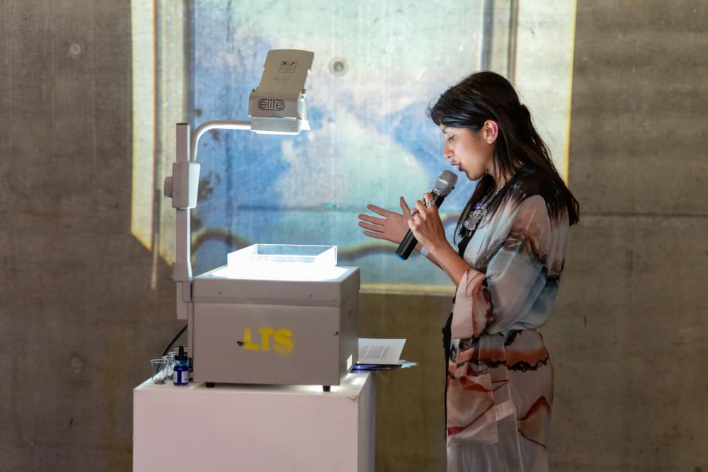 Becky standing at an overhead projector, speaking into a microphone