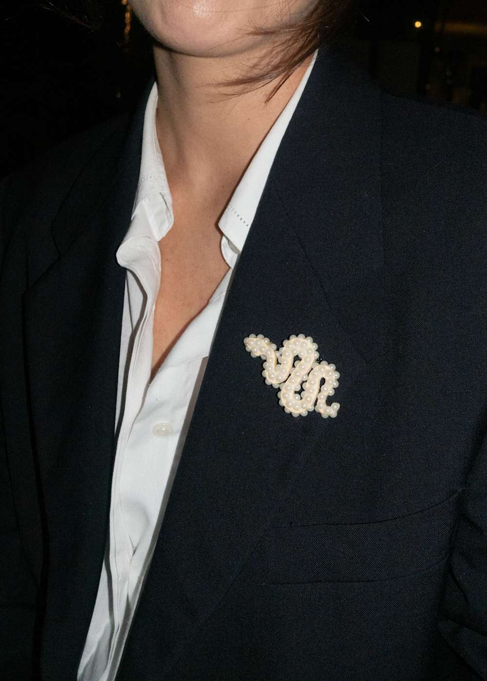 Close up of a black jacket with faux pearls pin on it