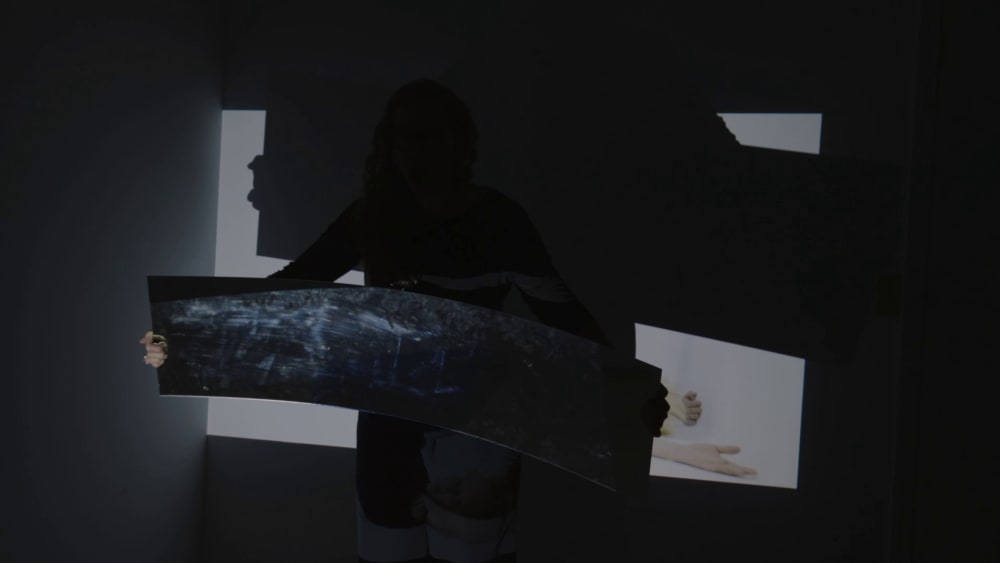 A person holding a sheet of transparent plastic in the dark