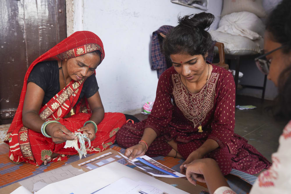Artisans seated on the floor examining materials