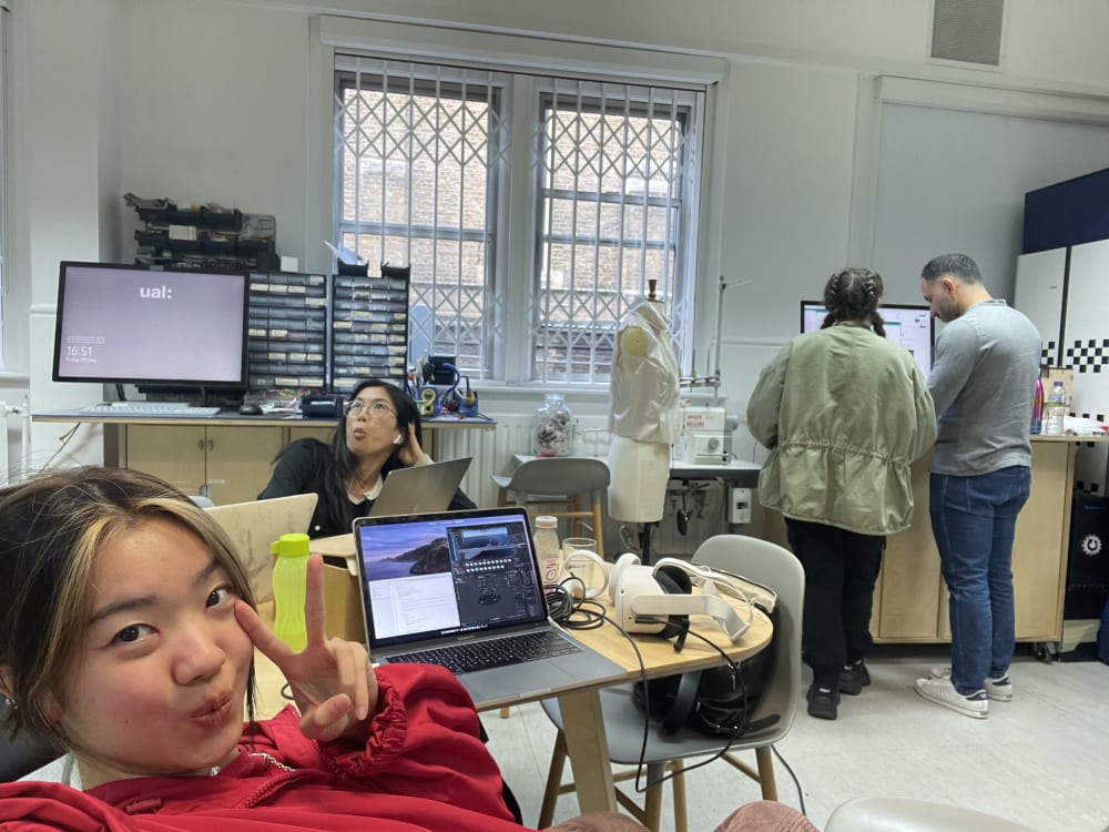 Jeanne taking a selfie with girl posing in the background and two people in the background working in the Digital Learning Lab Office 