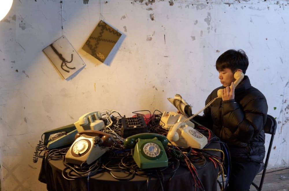 A person sat at a table listening to a telephone