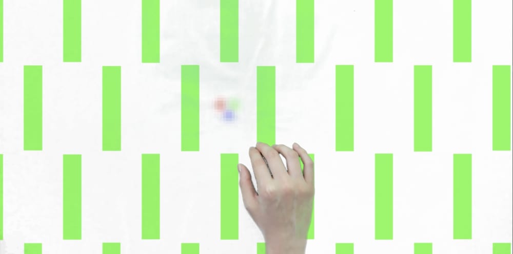A hand reaches across a screen covered in green and white rectangles