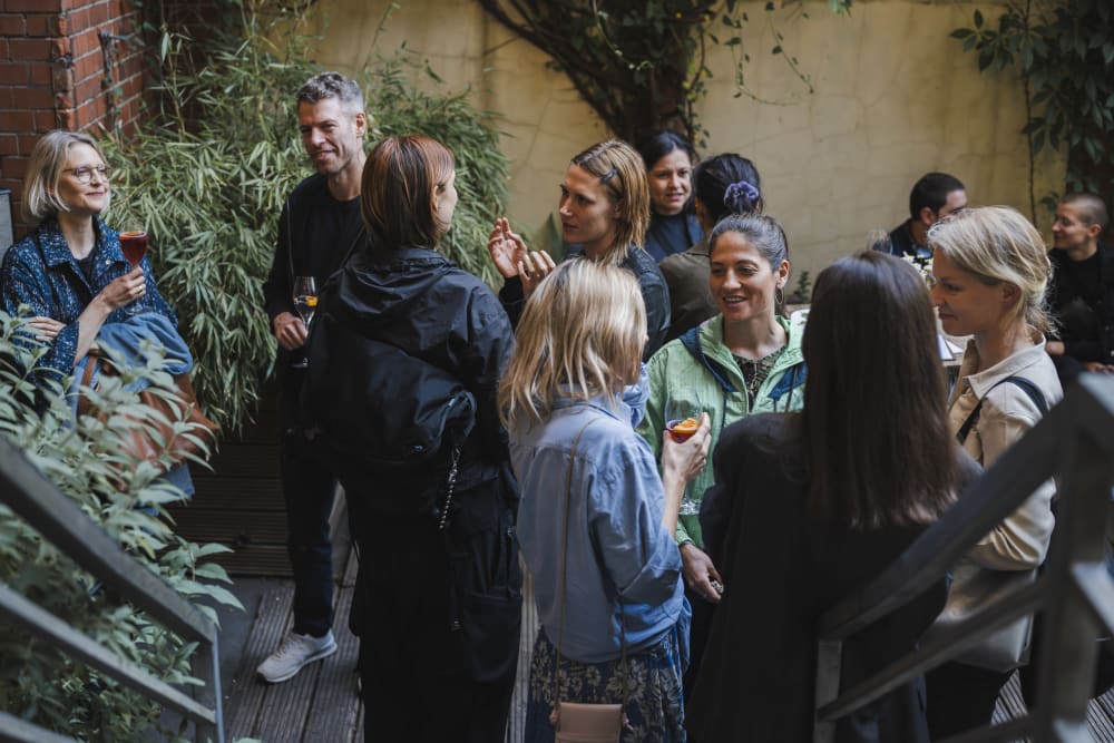 Guests stood outside chatting. At the forefront of the image are some metal steps