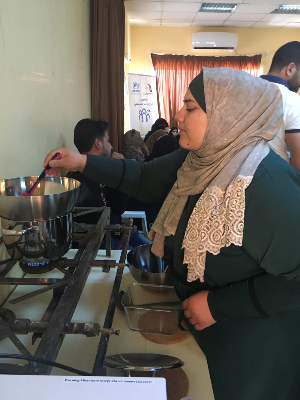 Ahlam is pictured making soap in a kitchen, using a stove to heat the ingredients.