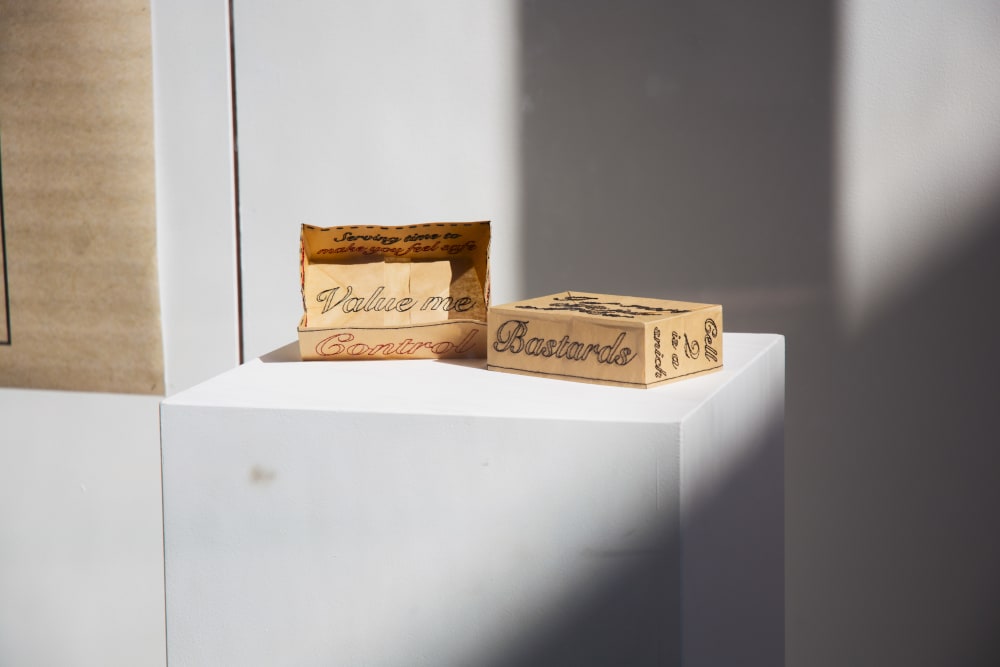 Brown paper box with embroidered words across.