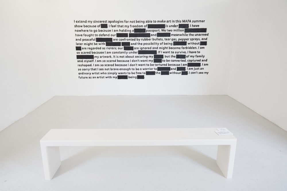 White room with black text piece on the wall and a white bench in front of it by student Puipui Ip.