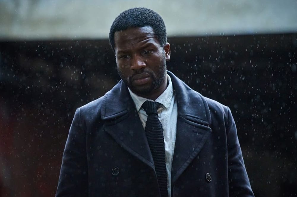 A still from Gangs of London featuring a man standing in the rain.
