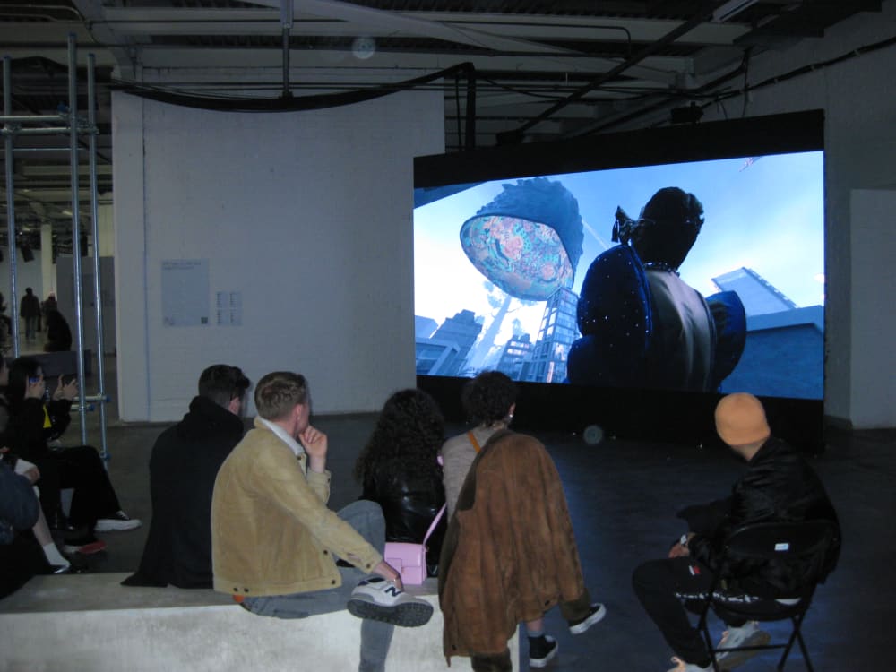 People sat watching the film on a projector at the LCF23 postgraduate exhibition