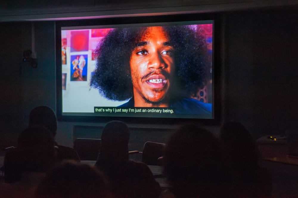 freeze frame from an alumni video played at the AoCA screening event