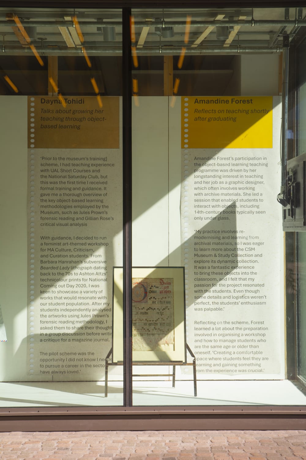 Ink and paint illumination on parchment exhibited behind a glass window in an outdoor windows gallery.