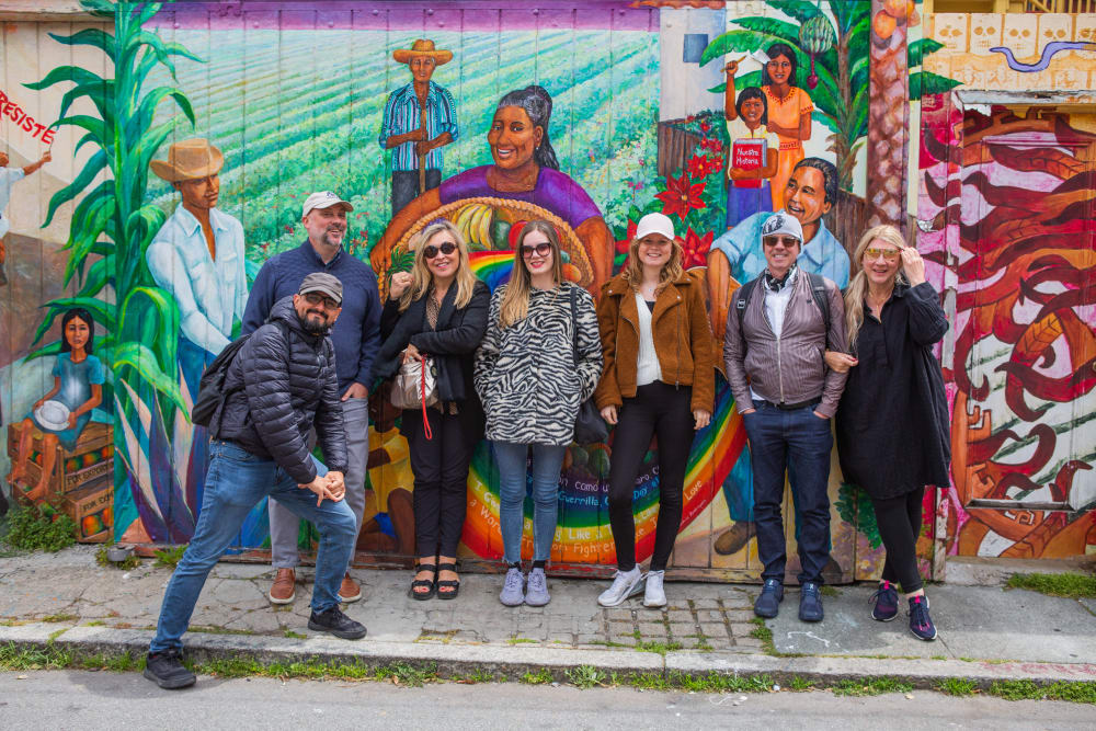 Group of people posing in front of colour mural on an outside wall