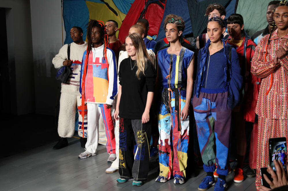 A group of diverse models and a young fashion designer standing in colourful clothing
