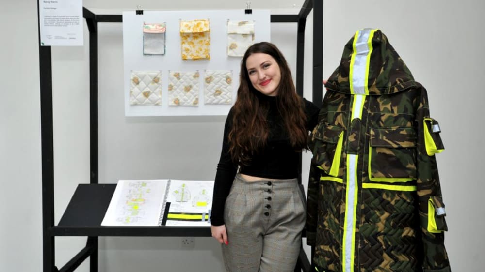 Student posing next to one of her designs