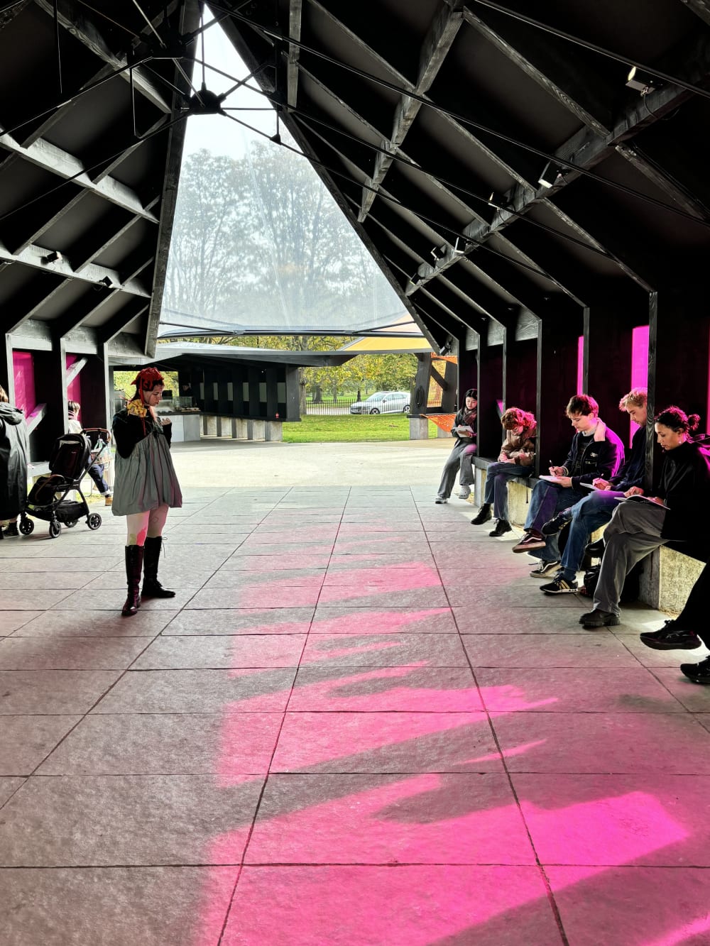 People sitting around a life model under a modern pavillion drawing